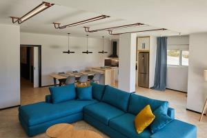ein Wohnzimmer mit einem blauen Sofa und einer Küche in der Unterkunft Flyin' High Luxury Suite in Metókhi