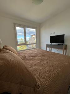1 dormitorio con 1 cama, TV y ventana en Depto en Los Canelos en Ushuaia