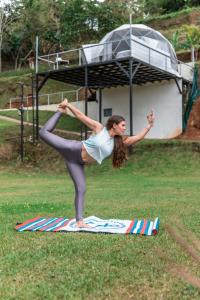 una mujer haciendo una pose de yoga en una tabla de surf en Badu Lodge Puriscal en Santiago