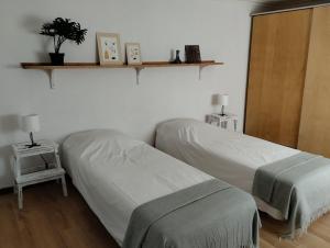 a bedroom with two beds and a shelf with two lamps at Abrigo dos Coelhos in Carcavelos