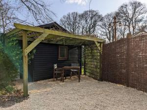 A Somerset Countryside Lodge في Holcombe: منزل به طاولة خشبية وسياج