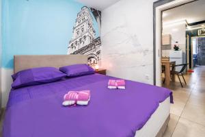 a bedroom with a purple bed with two towels on it at Tamaria in Split