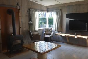 ein Wohnzimmer mit einem Holzofen und einem Tisch in der Unterkunft Kiefhoekhuisje in Hechtel-Eksel