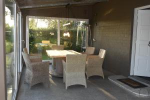 un patio con mesa y sillas en un porche en Kiefhoekhuisje, en Hechtel-Eksel