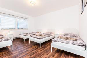 a group of four beds in a room with wood floors at Ferienwohnung Köln Stammheim in Cologne