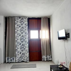 サンタ・ジュスタにあるAppartamento Fronte Lagunaの窓付きのドア、テレビが備わる客室です。