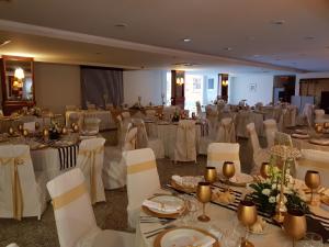 um salão de banquetes com mesas brancas e cadeiras brancas em Palace Hotel & Spa - Termas de Sao Vicente em Penafiel
