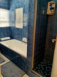 a blue tiled bathroom with a bath tub at La Grace Executive Guesthouse in Amsterdamhoek