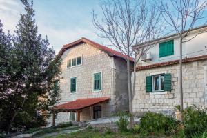 a stone house with green shutters and a tree at Tamaria in Split