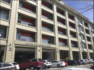 a large building with cars parked in a parking lot at Mapar Studio en Montevideo in Montevideo