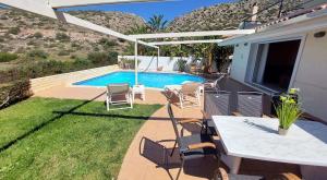 um pátio com uma mesa e cadeiras e uma piscina em Holiday villa SUNJOY close to the beach em Sounio