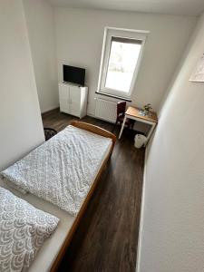 a bedroom with a bed and a desk and a window at Zimmervermietung Altes Zollhaus in Obernkirchen