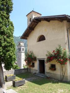 a building with a clock tower and flowers on it at CasaTati in Molina di Ledro