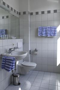a white bathroom with a toilet and a sink at Gasthaus Sternen Post in Oberried