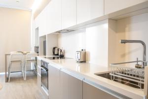 a kitchen with white cabinets and a sink at Mythical Spa Suite - GYM*Yoga Room*Pools in Protaras +30 photos