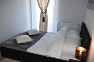 1 cama con sábanas y almohadas blancas y ventana en Apartament Kadzielnia, en Kielce