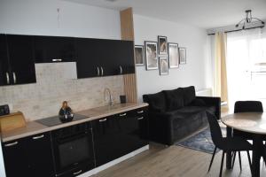 cocina con armarios negros, mesa y sofá en Apartament Kadzielnia, en Kielce