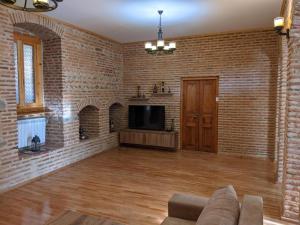 a living room with a couch and a tv in a brick wall at Guest House Anuki in Sighnaghi