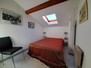 een slaapkamer met een bed en een stoel en een dakraam bij Maison Urrugne, 3 pièces, 4 personnes - FR-1-239-596 in Urrugne