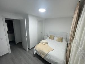 ein weißes Schlafzimmer mit einem Bett und einem Fenster in der Unterkunft Tu precioso piso en el centro de Torrejón in Torrejón de Ardoz