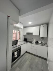 - une cuisine blanche avec évier et cuisinière dans l'établissement Tu precioso piso en el centro de Torrejón, à Torrejón de Ardoz