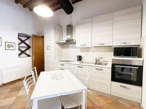 eine Küche mit weißen Schränken und einem Tisch mit Stühlen in der Unterkunft Casa Montanini Centro Storico in Siena