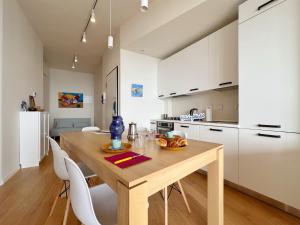 una cucina con tavolo in legno e armadietti bianchi di Seaside Luxury Apartment by Holiday World a Cogoleto