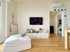 a white living room with a tv on the wall at Seaside Luxury Apartment by Holiday World in Cogoleto