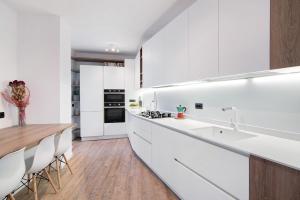 cocina con armarios blancos y mesa de madera en Casa Glicine, en Domaso
