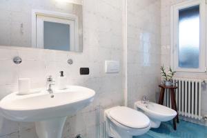 a white bathroom with a sink and a toilet at Casa Glicine in Domaso