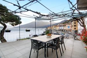 einen Tisch und Stühle auf einer Terrasse mit Blick auf das Wasser in der Unterkunft Casa Glicine in Domaso