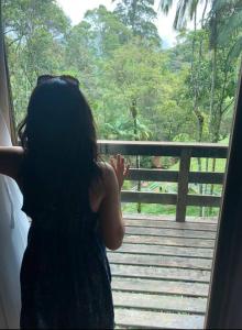 a girl looking out of a window at a forest at Recanto dos Sonhos Guest House in Lumiar