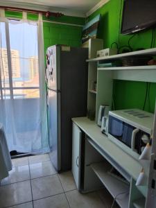 une cuisine avec des murs verts et un réfrigérateur dans l'établissement Homestay Iquique, à Iquique