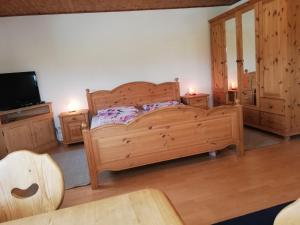 1 dormitorio con cama de madera y TV en Ferienapartment Brandstatt en Seeg