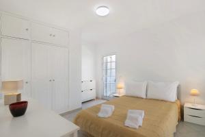 a white bedroom with a large bed and white cabinets at Villa Galé in Guia