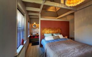 a bedroom with a large bed with a red wall at Villa Azura in Tholen