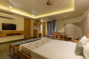 a hotel room with a bed and a flat screen tv at Indus Suites in Nagpur +16 photos