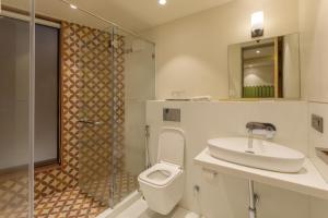 a bathroom with a toilet and a sink and a shower at Indus Suites in Nagpur