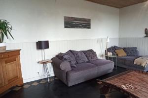 a living room with a couch and a table at Hoeve Korenzegen. Oase van rust dichtbij strand in De Haan