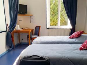 a room with two beds and a desk and a window at La Table Des Bons Peres in Bislée