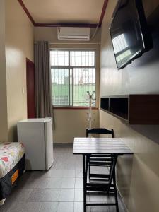 a room with a kitchen with a table and a refrigerator at Hotel Fortaleza Manaus in Manaus