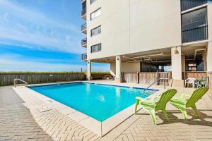 a swimming pool with two green chairs next to a building at Sundunes 122 in Navarre