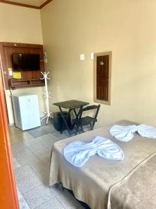 a room with two beds and a table and a kitchen at Hotel Fortaleza Manaus in Manaus