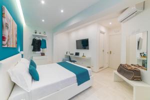um quarto branco e azul com uma cama e uma televisão em I Mori dell’Etna em Giardini Naxos