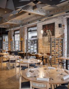 a restaurant with tables and chairs and a brick wall at Hotel Tayko Bilbao in Bilbao