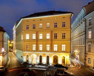 a large yellow building with cars parked in front of it at Charles Bridge Palace in Prague