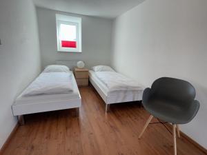ein Zimmer mit 2 Betten und einem Stuhl darin in der Unterkunft Ferienwohnung Nord in Fehmarn