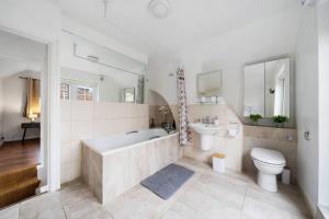 a bathroom with a tub and a toilet and a sink at Charming Cottage in Hampstead Heath in London
