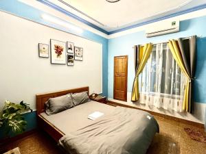 Un dormitorio con una cama con paredes azules y una ventana en Nhà nghỉ Thành Trung, 