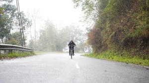 a person riding a bike down a road in the rain at Yellow Sapphire, Premium Sikkimese Homestay in Gangtok